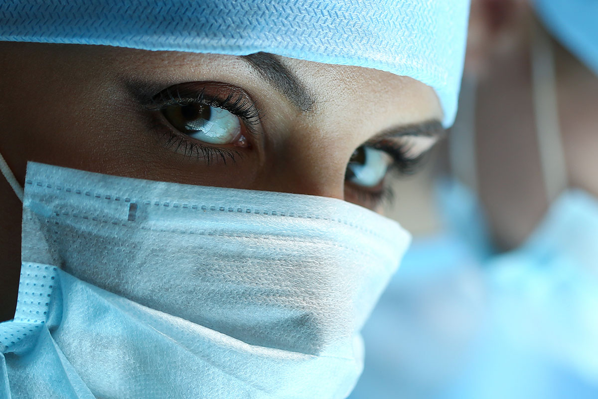 Close-up of female medical professional wearing a surgical cap and mask