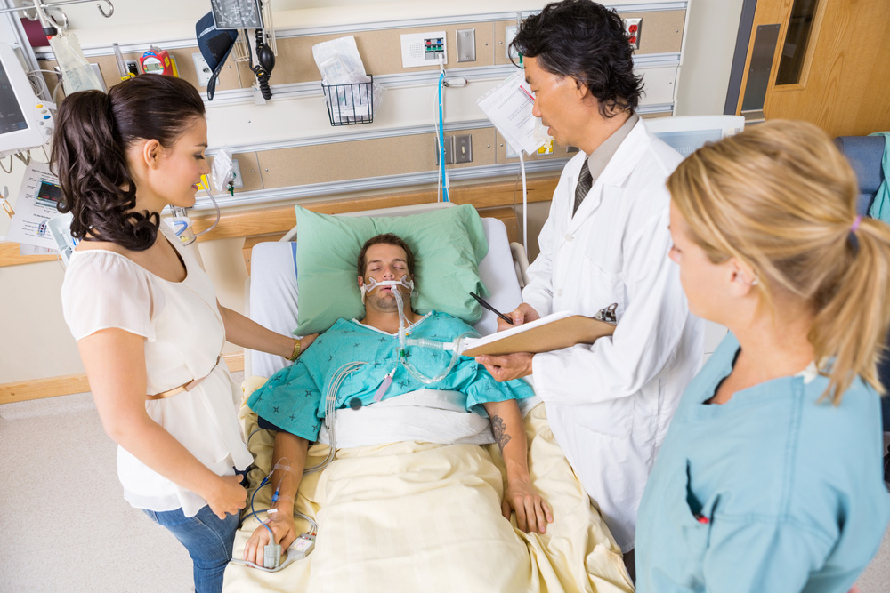 Patient on ventilator surrounded by family and medical professionals