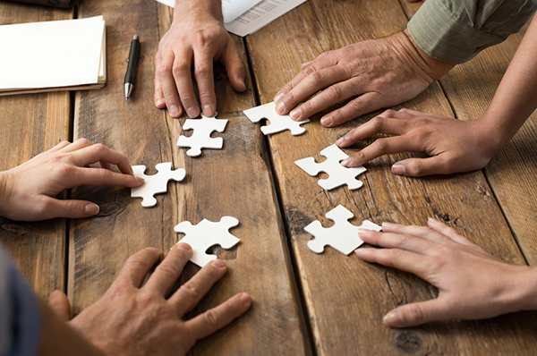 A group of people each holding a jigsaw puzzle piece
