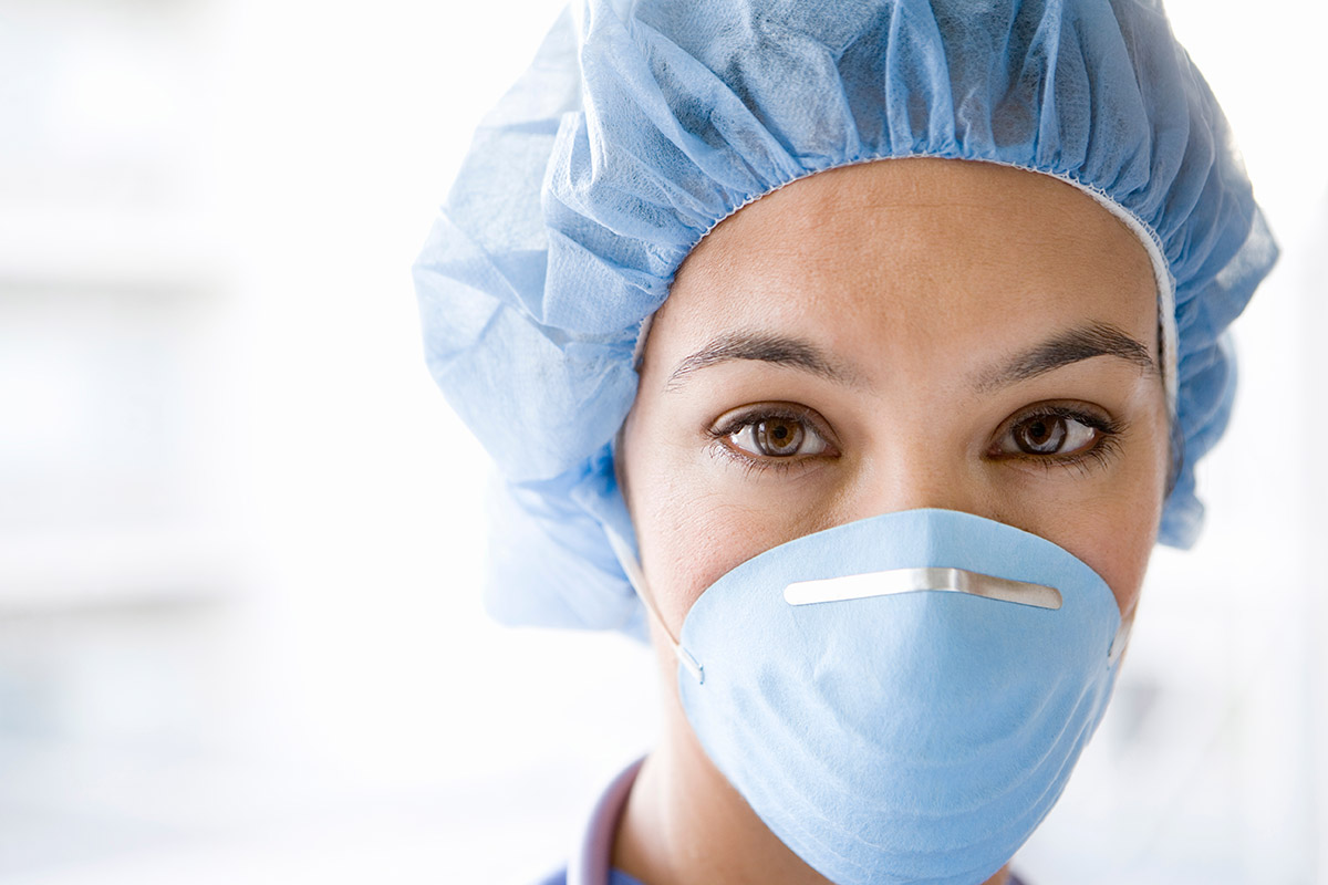 Female medical professional in a disposable cap and mask