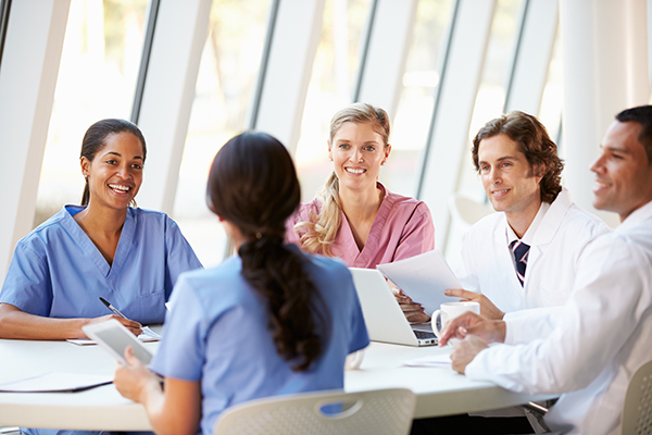 Medical professionals in a meeting around a table smiling and chatting.