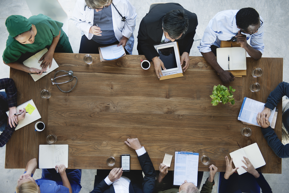 Bird's eye view of professionals in the medical field sitting around a table in a meeting