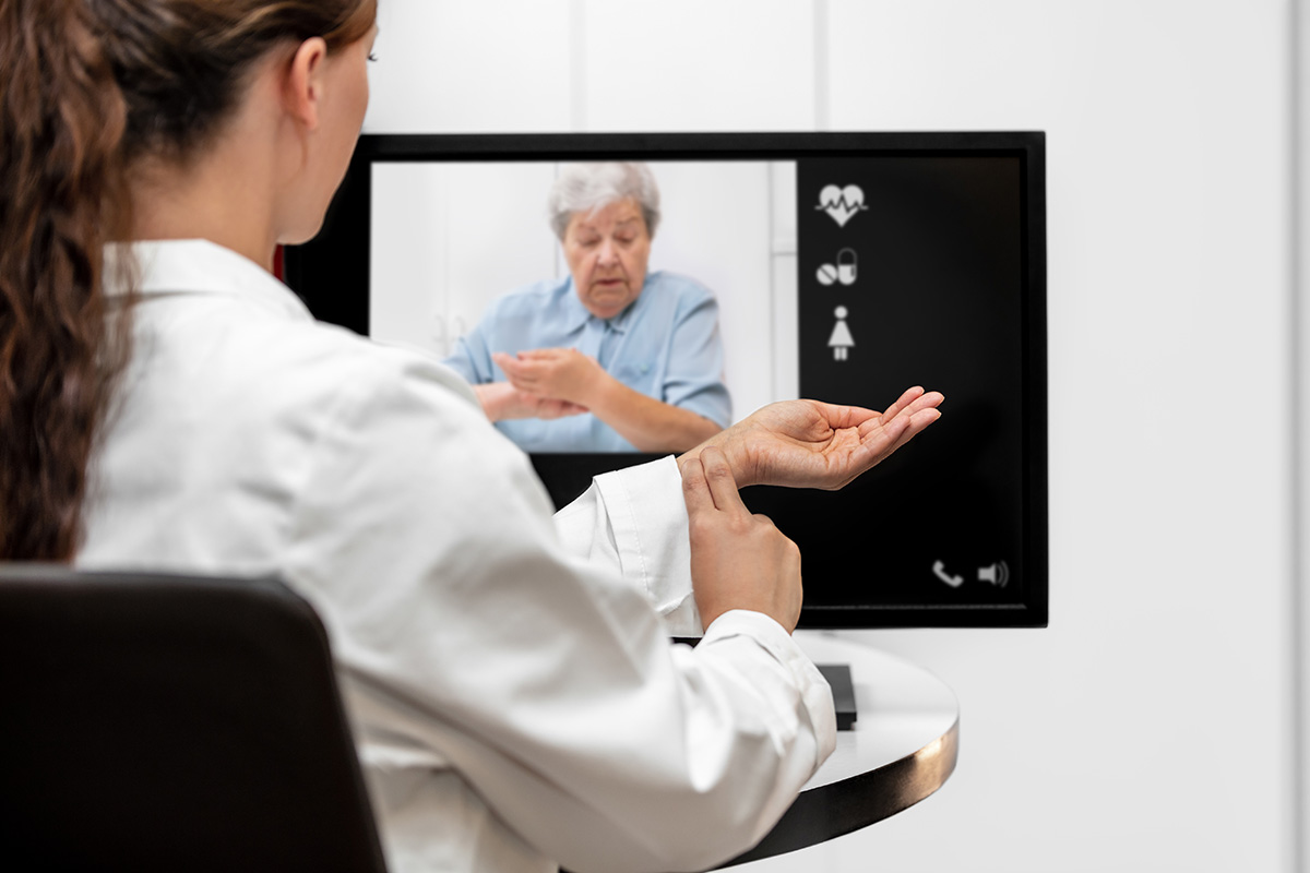 Female medical professional takes pulse with patient over telehealth
