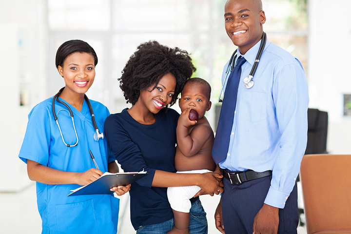 Smiling pediatric medical professionals with mother holding her baby