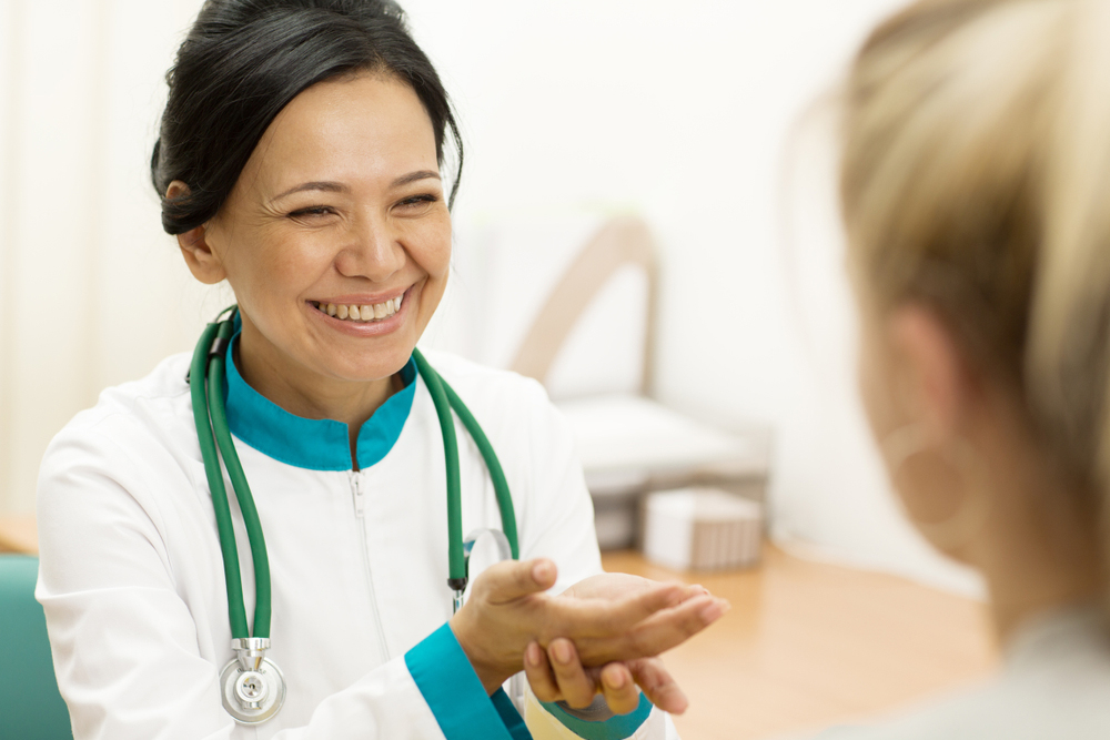 Female medical professional smiling and speaking to a patient