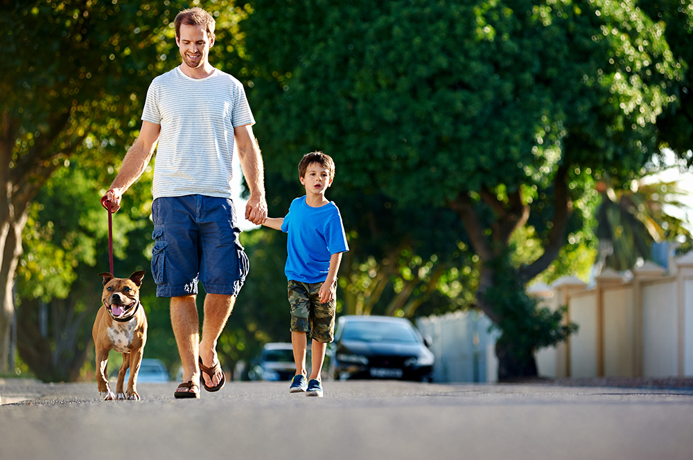 Man walking outside with dog and boy