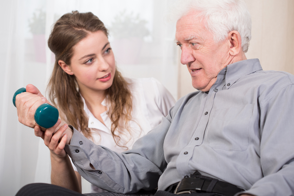 Elderly man works on therapy of right arm with physical therapist