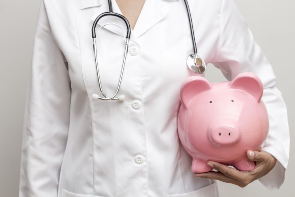 Doctor with piggy bank in hand representing medical costs, horizontal; healthcare financial outlook