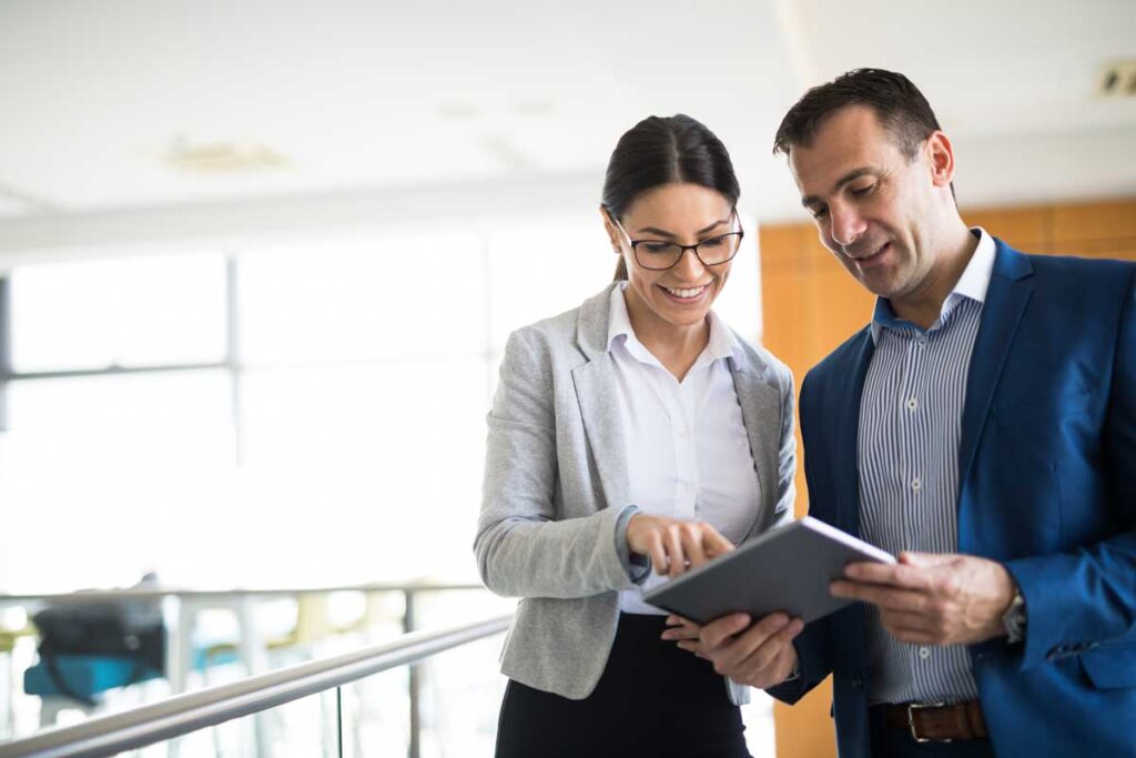 Professional woman and man overlooking tablet device for managed IT services.